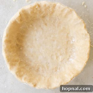 Finished golden brown pie in a white ceramic pie dish, ready to be sliced and served.