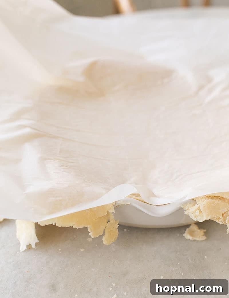 A hand gently flipping the rolled-out pie crust into a pie dish, demonstrating the careful transfer technique.