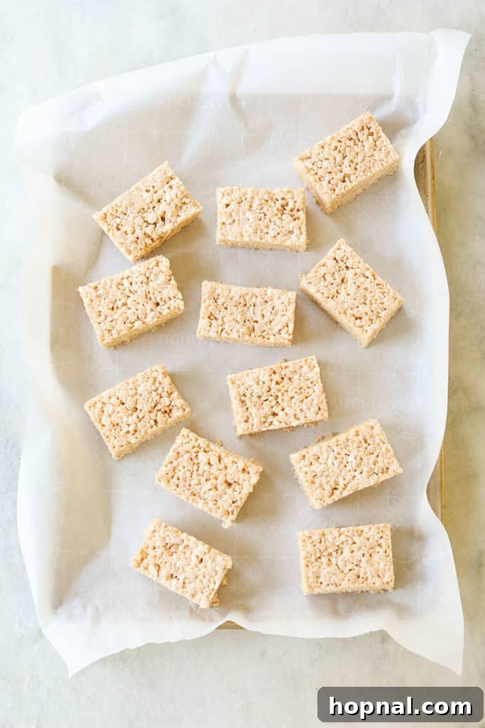Cutting the cooled Rice Krispie treats into perfect rectangles with a buttered knife.