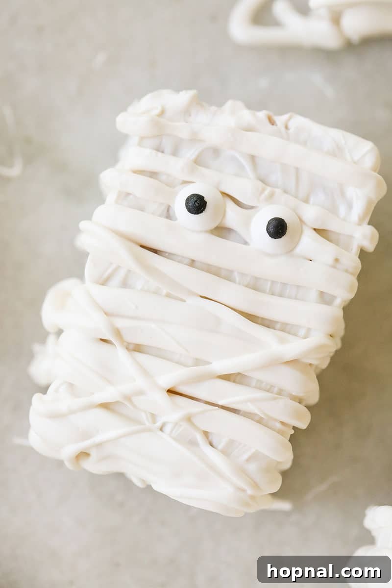 A single white chocolate mummy Rice Krispie treat with two candy eyes, ready to be enjoyed.