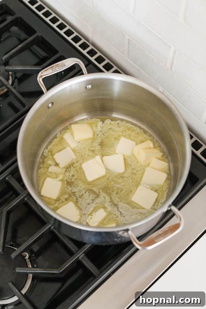 Melting butter in a saucepan over medium heat to begin the browning process for Rice Krispie treats.