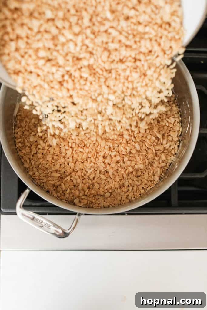 Mixing Rice Krispies cereal into the warm, gooey marshmallow and browned butter mixture.