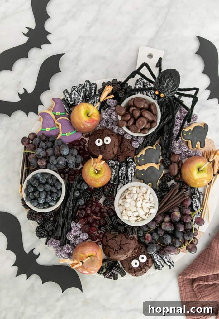 A vibrant Halloween dessert platter overflowing with various candies, cookies, and sweet treats arranged for a festive party.