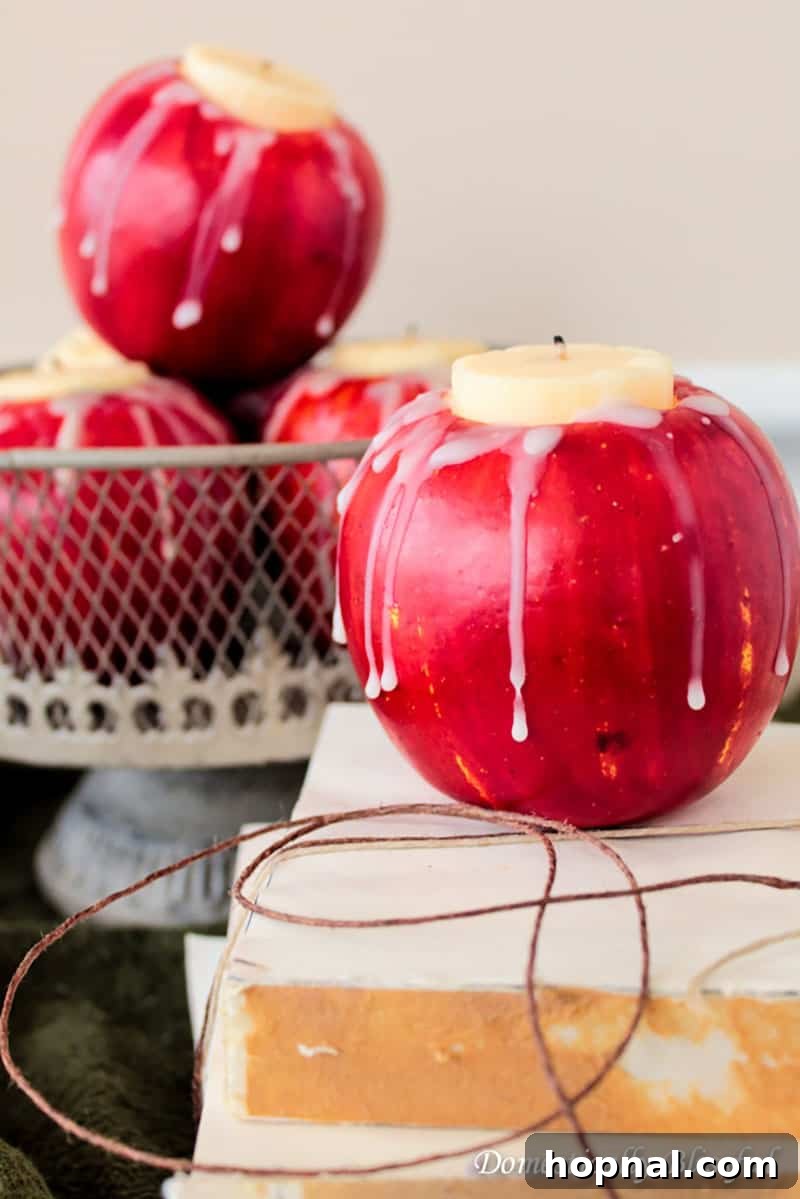A bright red apple with a tealight candle nestled in its hollowed-out center, serving as a creative and natural candle holder for Halloween.