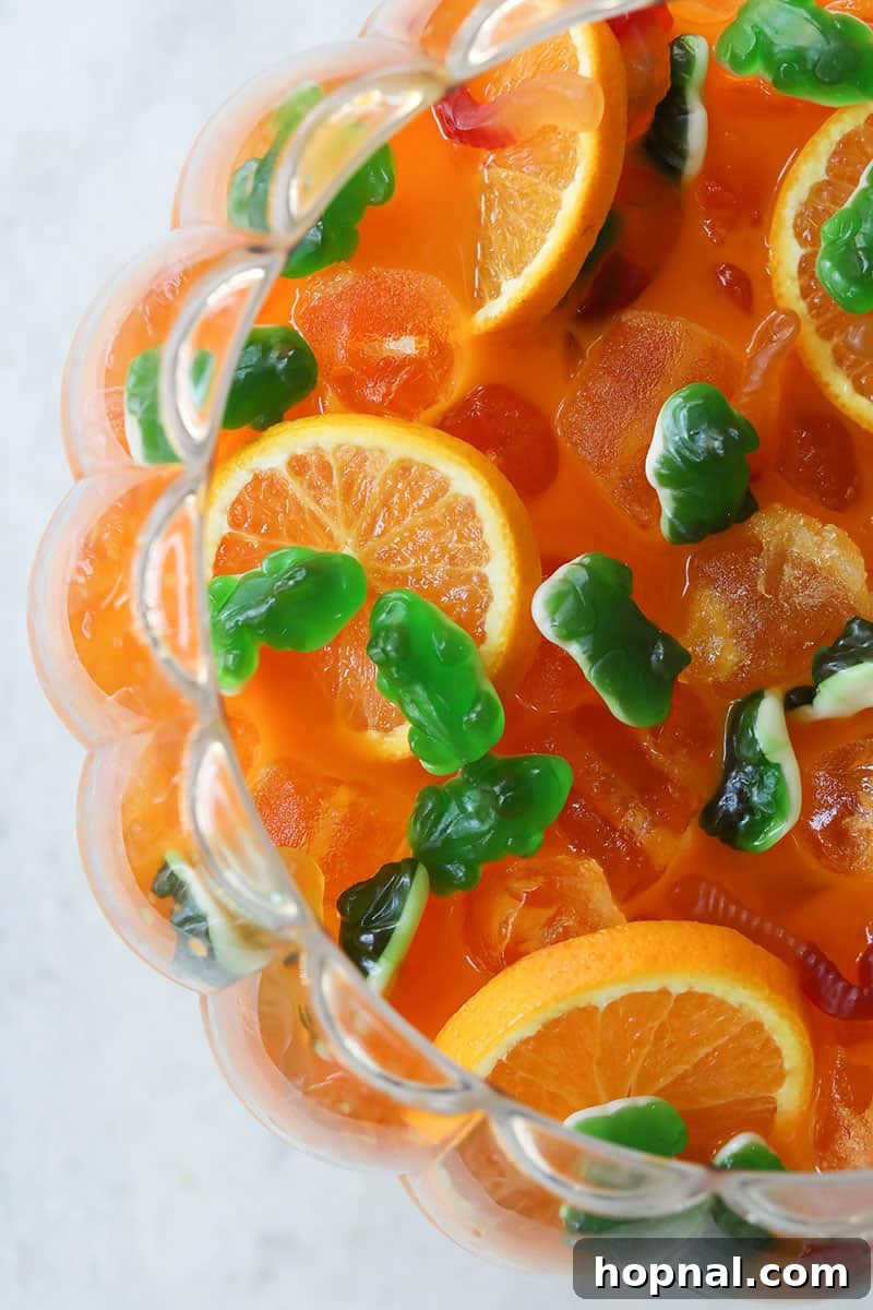 Halloween punch with gummy worms and gummy frogs for garnish in a punch bowl.
