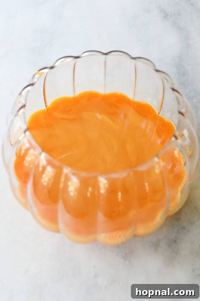 Orange punch in a glass pumpkin bowl, ready for serving.