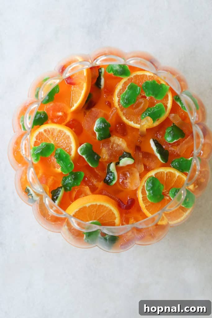 Halloween punch bowl filled with bright orange kids’ punch, garnished.