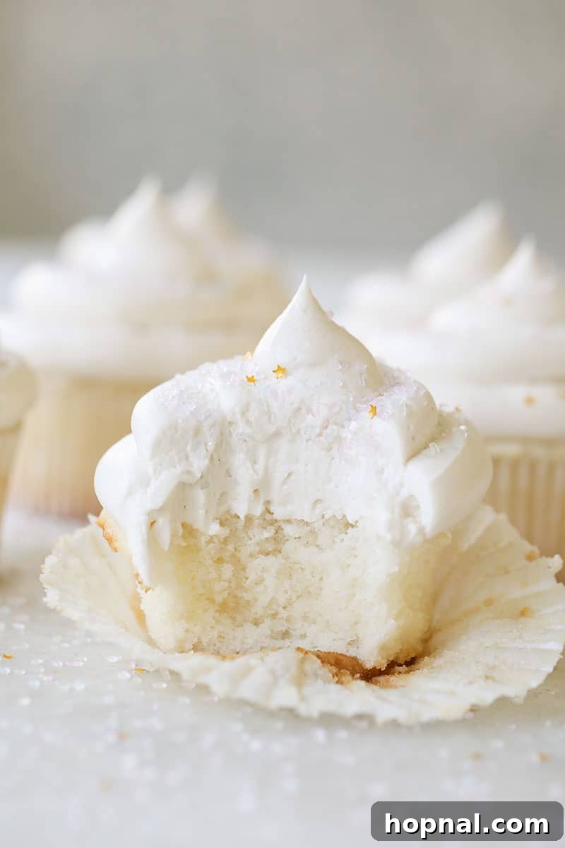 Vanilla cupcake with a bite taken out of it and gold star sprinkles on top.