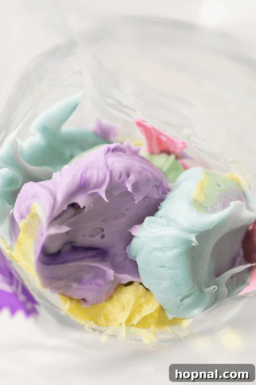 Close-up of a piping bag filled with vibrant, colorful homemade buttercream frosting, ready for decorating festive treats.