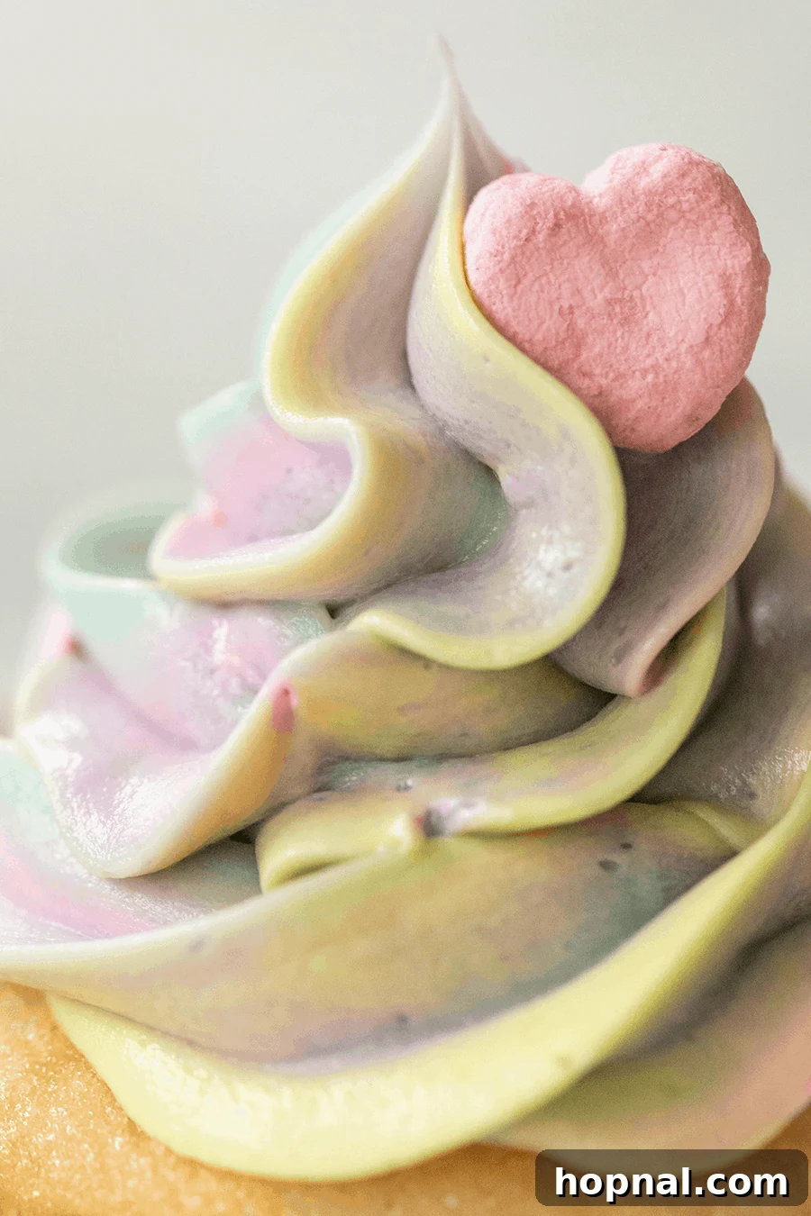 Close-up of a colorful homemade buttercream frosting swirled with a festive Lucky Charms heart on top, perfect for themed desserts.