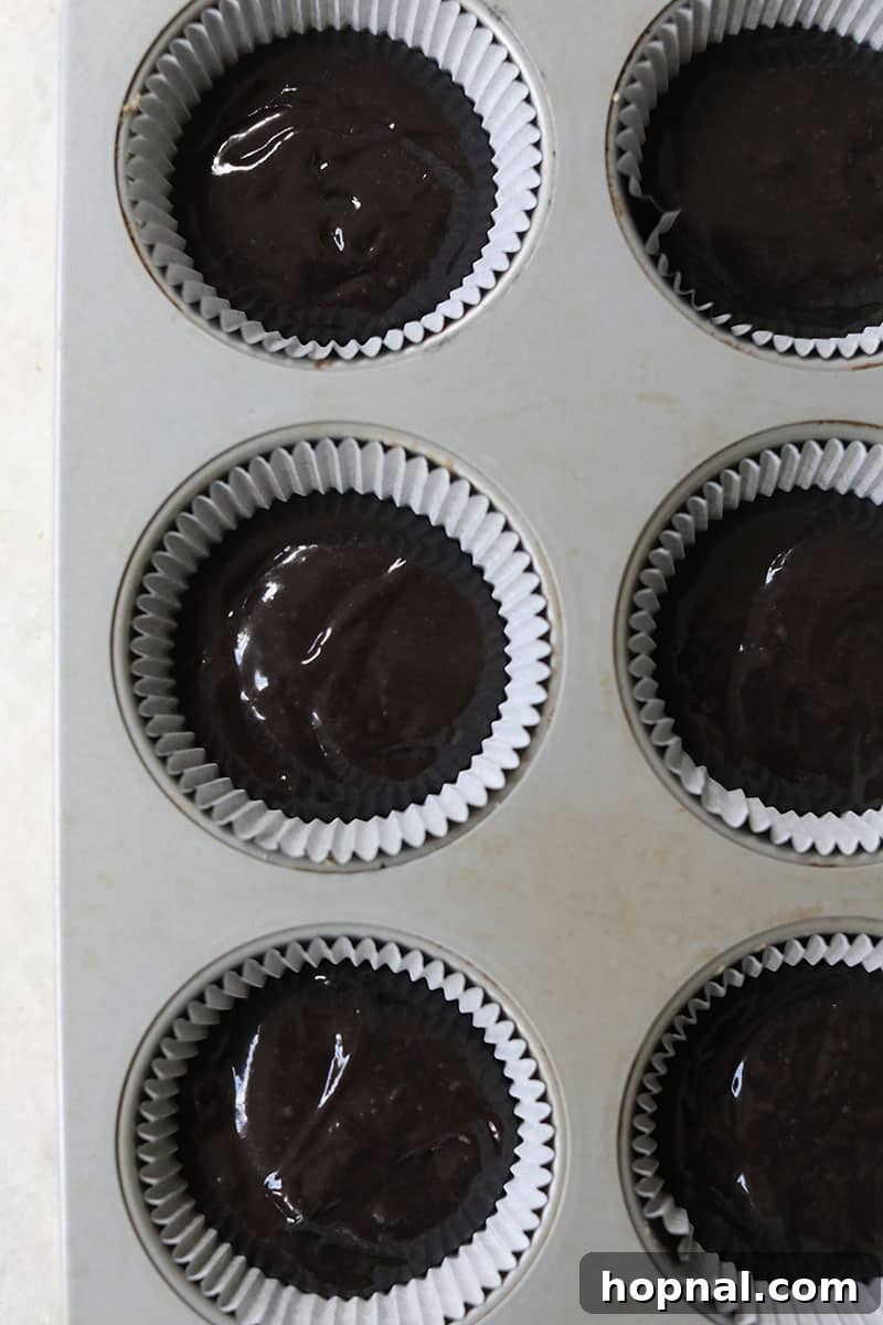 Black velvet cupcakes nestled in a cupcake tin, perfectly filled and ready to be baked in the oven.