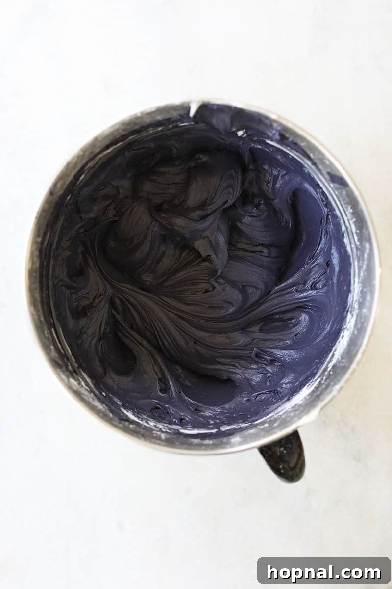 Rich, whipped black cream cheese frosting, ready to adorn black velvet cupcakes with its velvety texture and deep hue.