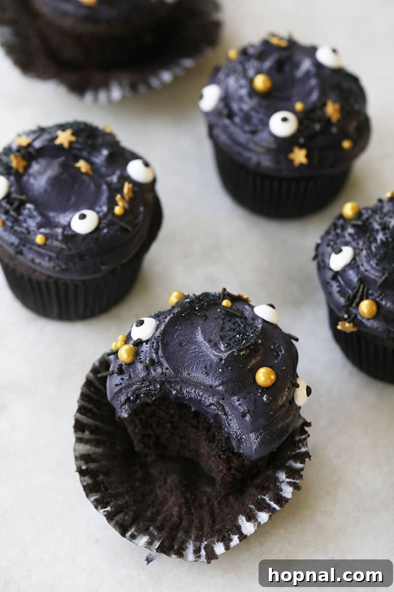 A collection of black velvet cupcakes, some with cream cheese frosting and sprinkles, presented as a delightful Halloween dessert.