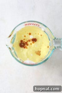 Wet ingredients for black velvet cupcakes in a measuring cup.