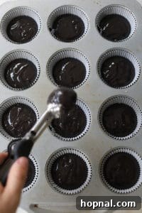 Cupcake liners being filled with black velvet batter.