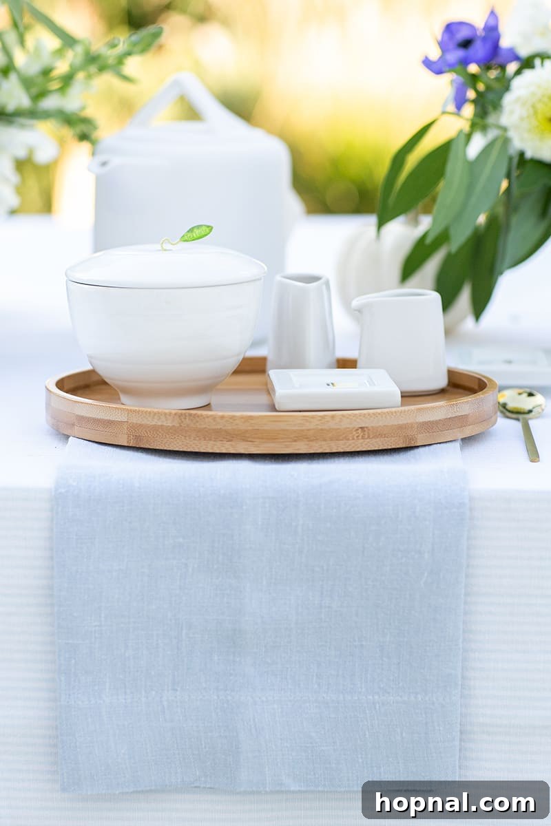 An elegantly set tea party table featuring crisp blue linens, matching tea sets, and charming floral accents, ideal for a bridal shower.