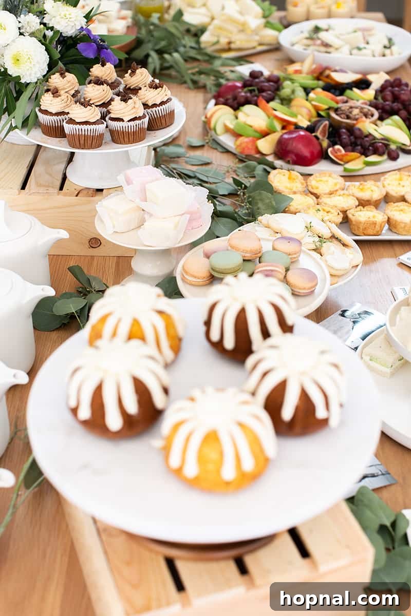 A lavish table laden with an assortment of tea party bridal shower foods, including sandwiches, pastries, and fresh fruit.