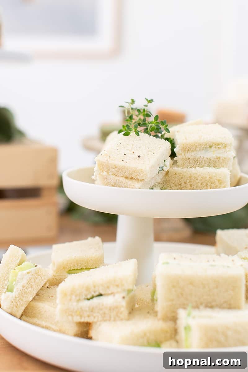 Exquisitely arranged tea party sandwiches, cut into perfect bite-sized portions, presented on a sleek, modern platter.