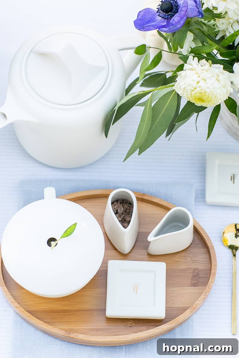 A charming tea set, accompanied by sugar and fresh flowers, sits beside a modern kettle for an elegant bridal shower.