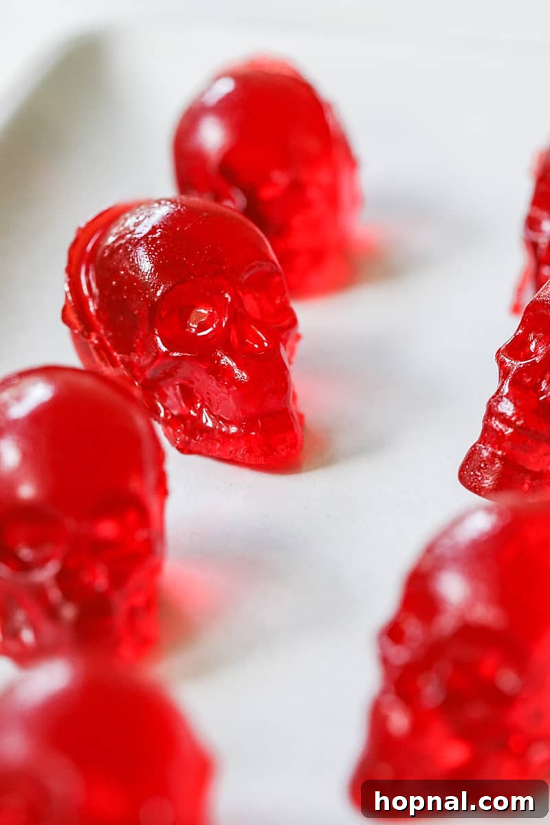 Bright red skull jello shots arranged on a pristine white plate, perfect for a Halloween celebration.