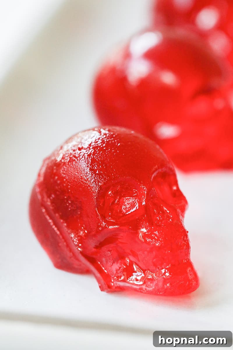 A solitary, striking red skull jello shot positioned elegantly on a white plate, symbolizing a spooky Halloween treat.