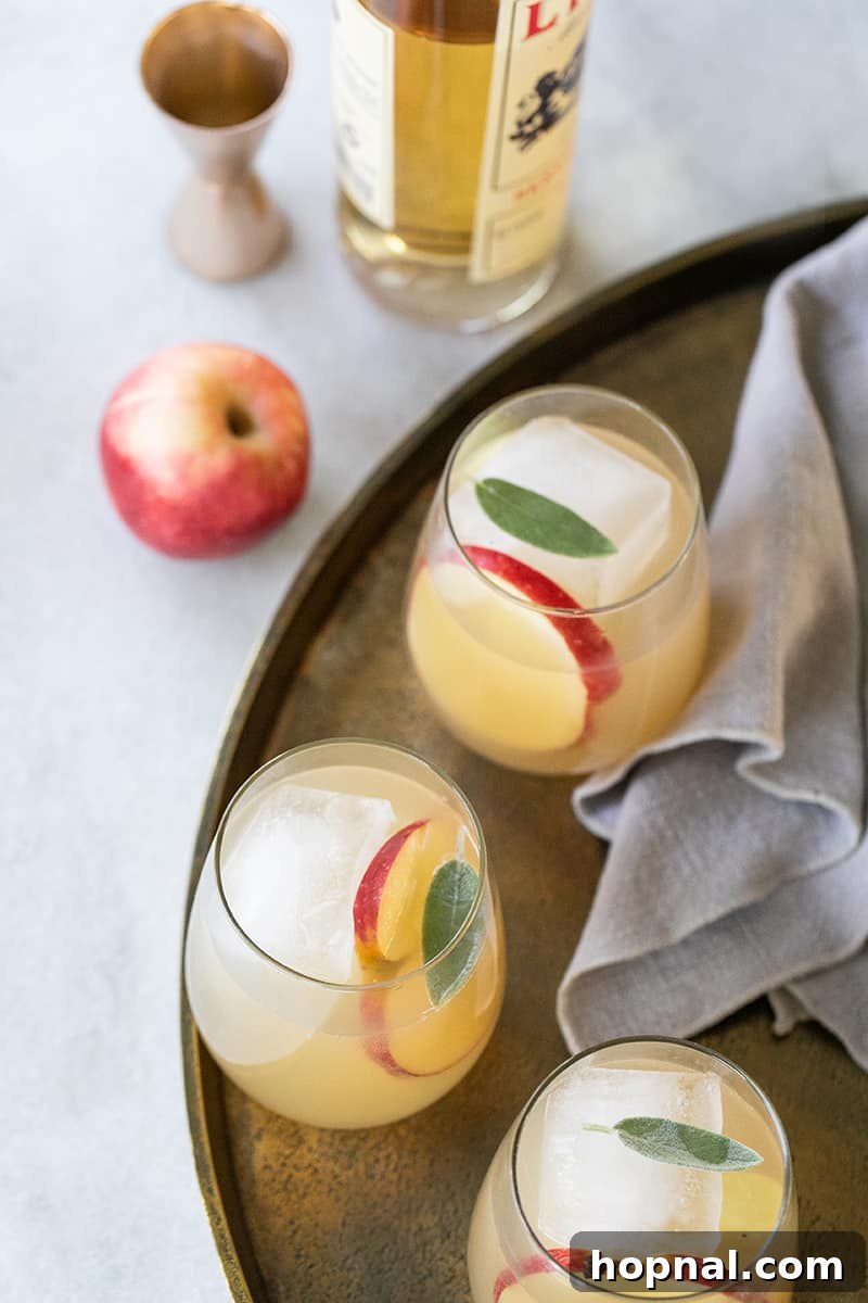 Sparkling Apple Ginger Wine Spritzer Your Fall Drink 5 Apple cocktail spritzer for Thanksgiving, arranged on a gold tray with fresh apples and Lillet.