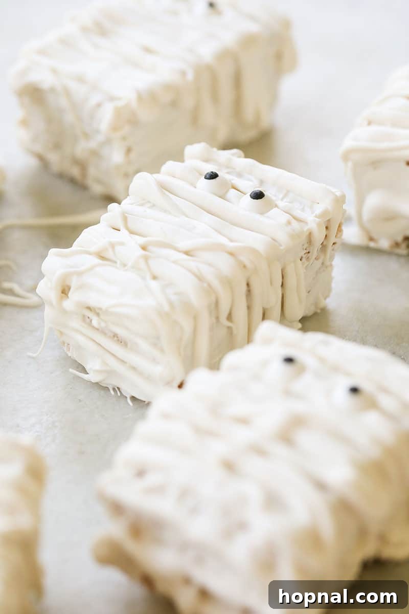 Adorable Rice Krispie Treat Mummies, decorated with white candy melts and playful sprinkle eyes, ideal for children's Halloween parties.