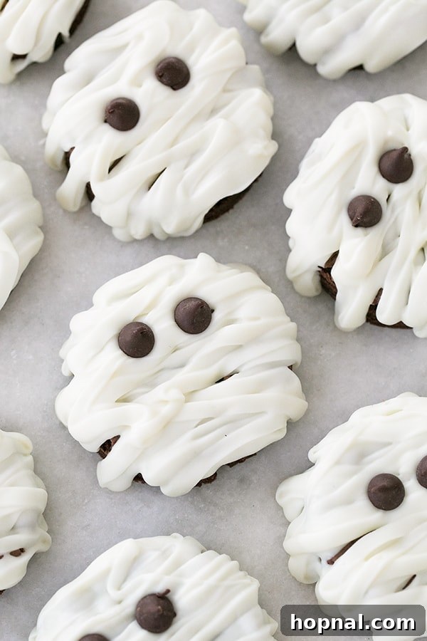Cute mummy brownies, decorated with white icing and candy eyes, perfect as a bite-sized Halloween treat for kids.