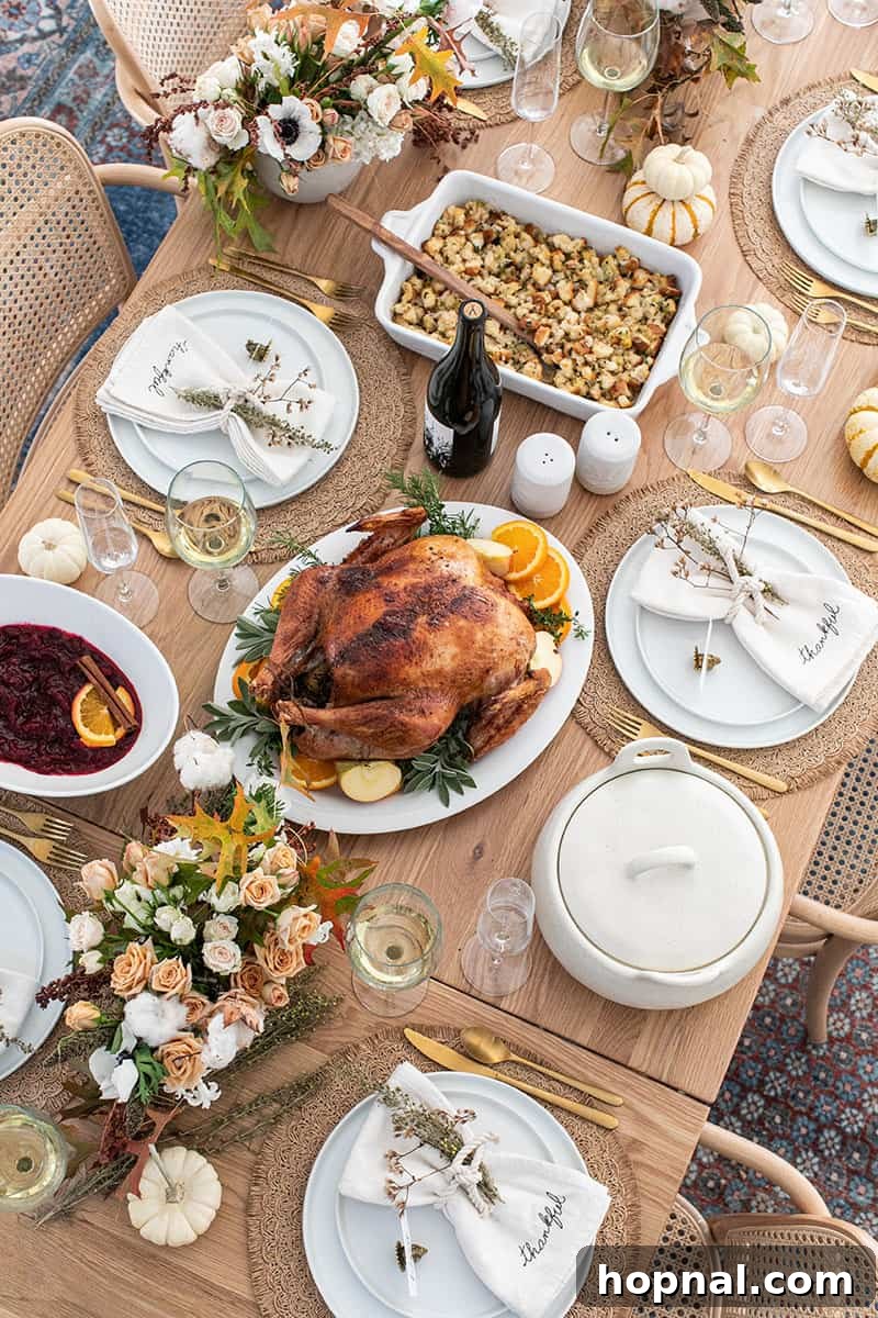 A beautifully set Thanksgiving table laden with a roasted turkey, fresh flowers, wine, stuffing, and cranberry sauce, ready for a festive meal.