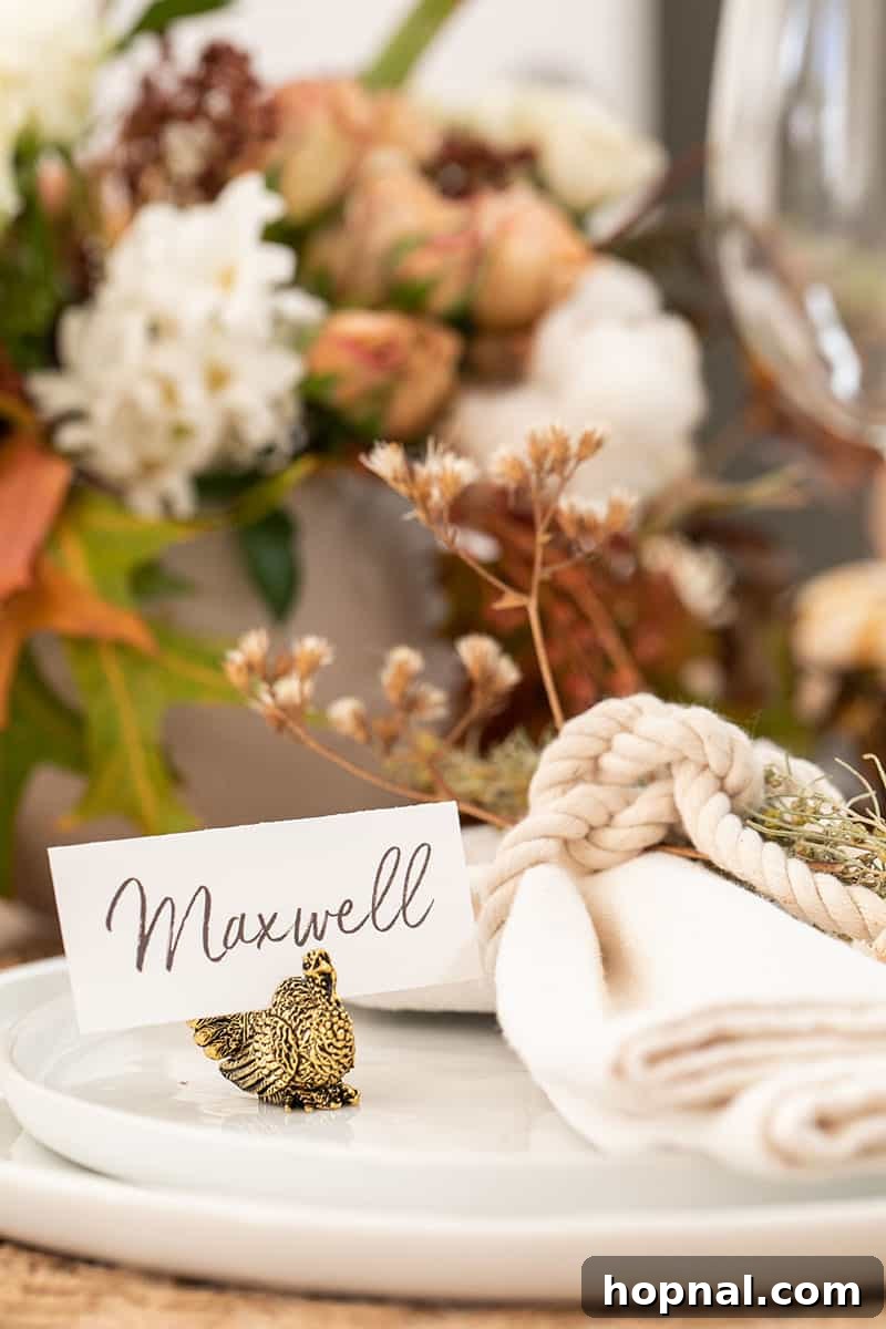 Close-up of elegant place cards held by small gold turkey figurines on a Thanksgiving table, adding a personalized and festive touch.
