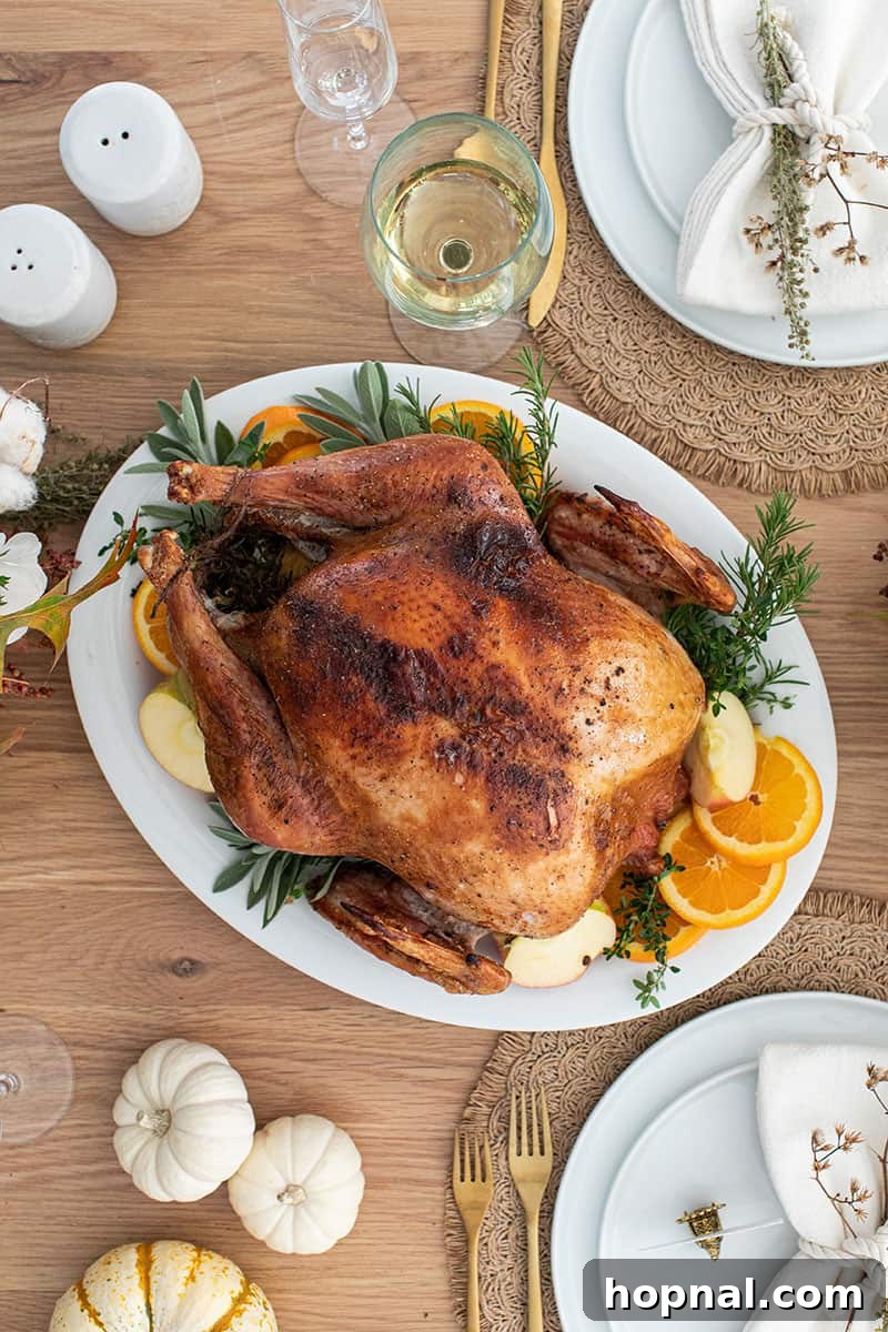 A beautifully roasted turkey presented on a pristine white platter, garnished and ready to be carved for Thanksgiving dinner.
