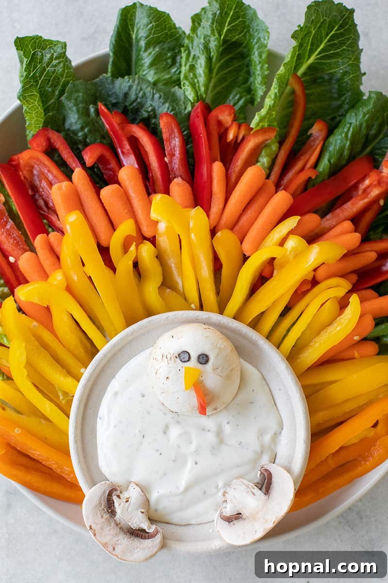 Vibrant Thanksgiving turkey vegetable platter featuring red, orange, and yellow bell peppers, baby carrots, and green leaf lettuce, perfect for a festive kids' snack table.