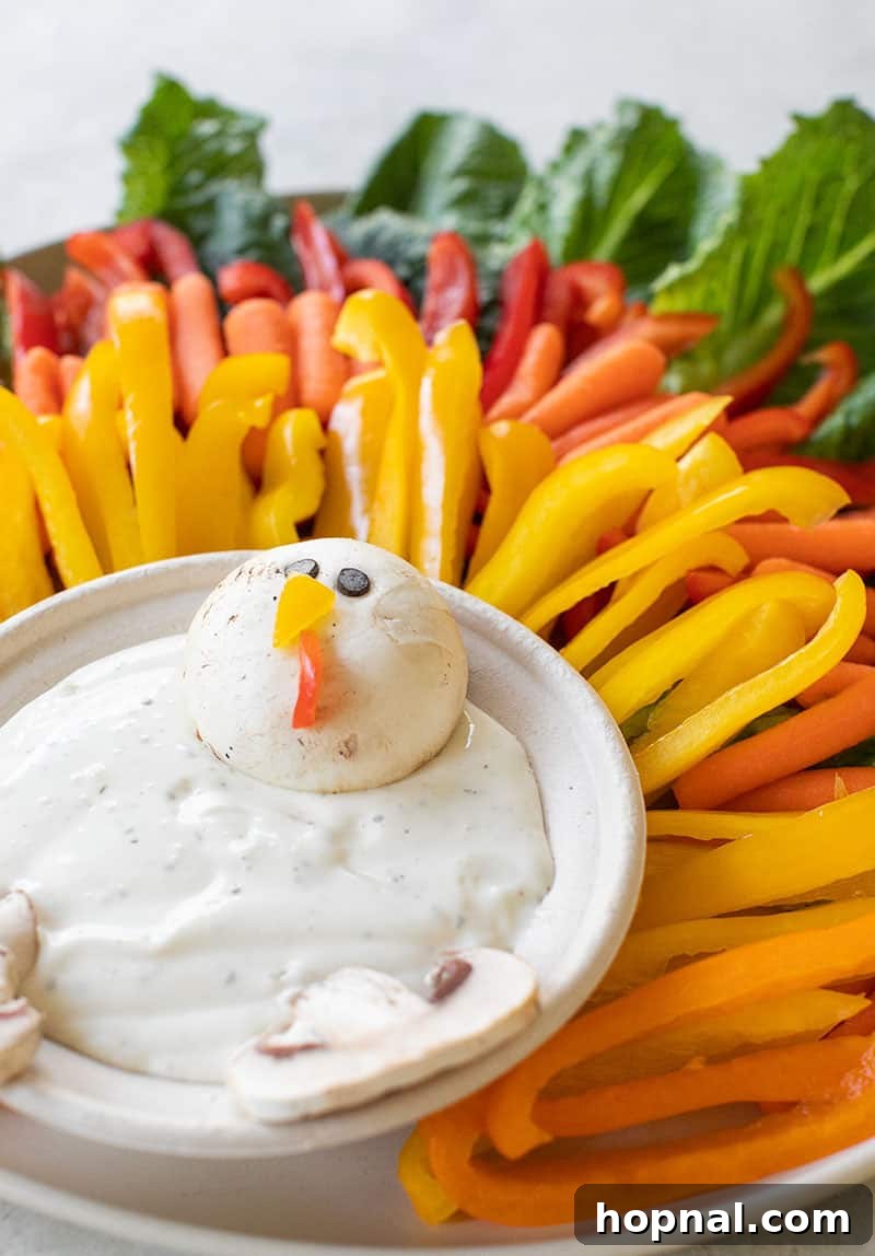 Thanksgiving appetizer platter for children, creatively arranged with fresh vegetables and creamy ranch dip to form the shape of a festive turkey.