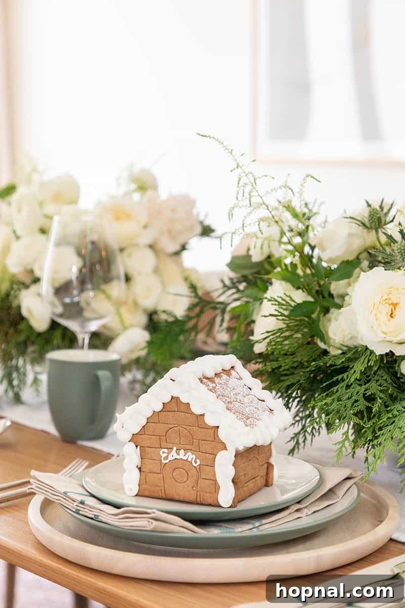 A beautifully set Christmas table featuring a gingerbread house centerpiece amidst festive decor and drinkware.