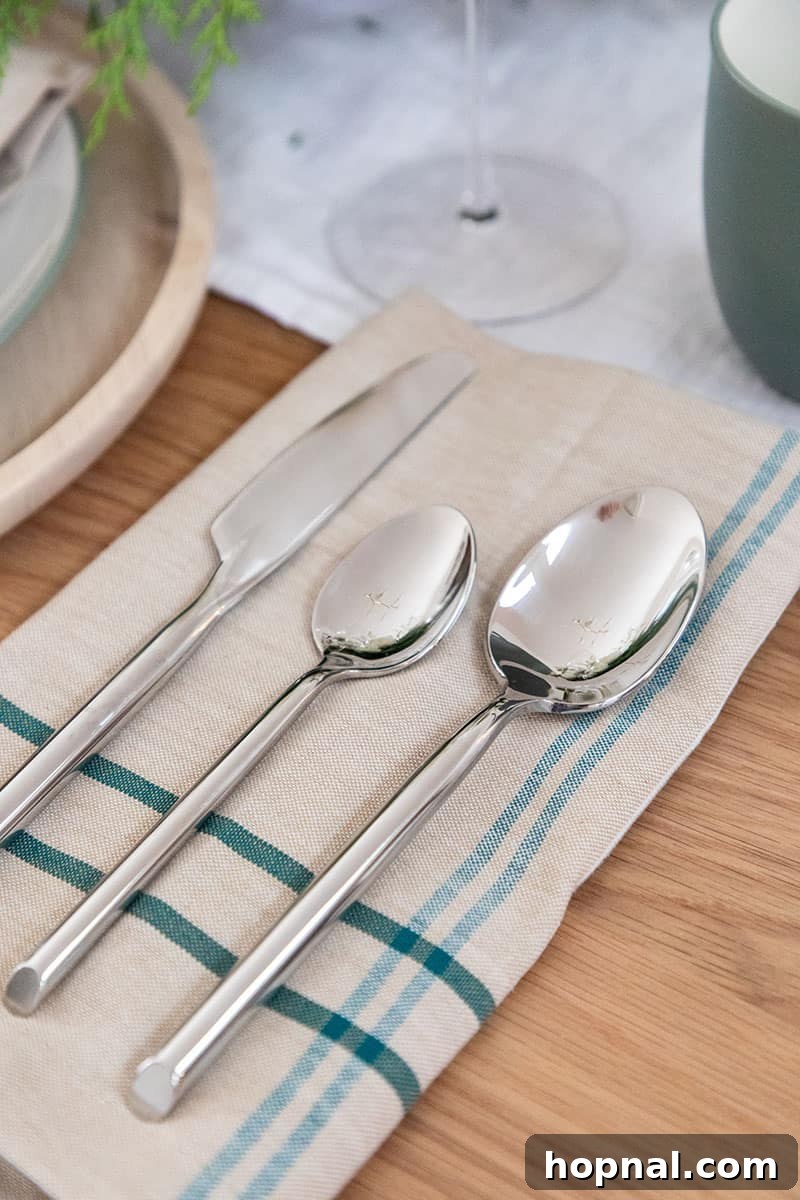 Elegant Fortessa flatware laid on a teal and green napkin, perfect for a Christmas table setting.