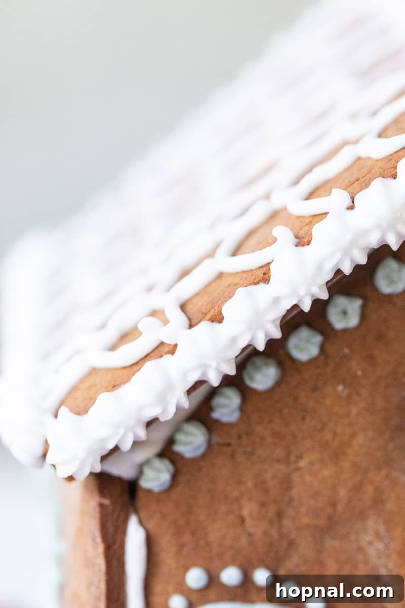 Detail shot of a gingerbread house roof decorated with fluffy white icing and colorful candies, illustrating the icing's decorative versatility.
