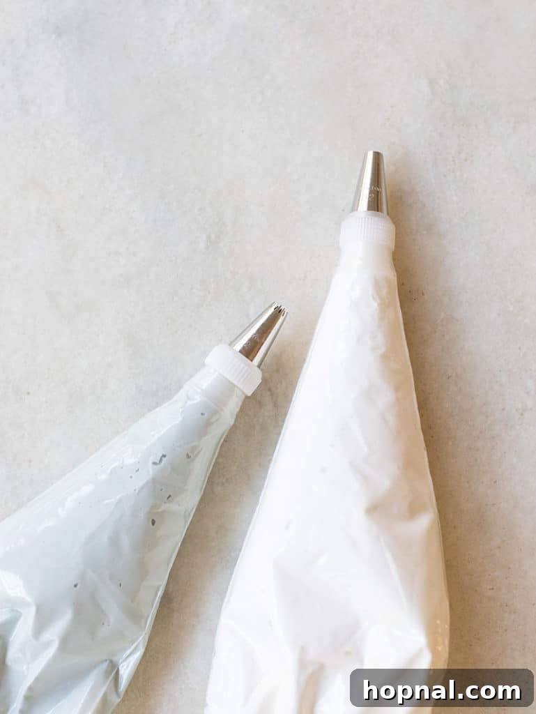 Two piping bags, neatly filled with white gingerbread house icing, ready for festive decorating.