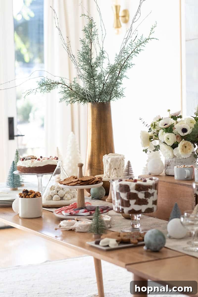 The Ultimate Guide to a Showstopping Christmas Dessert Display 2 Christmas dessert table adorned with cakes, cookies, fresh flowers, and a brass vase holding natural branches.