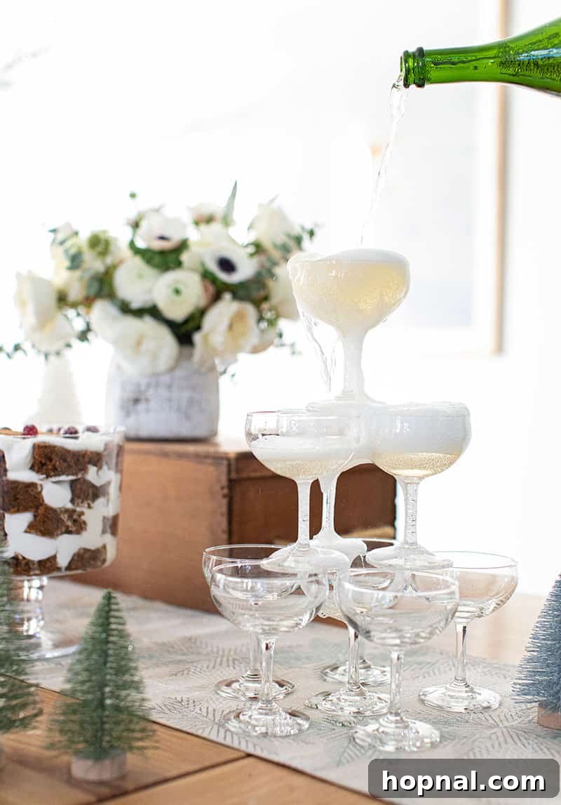 The Ultimate Guide to a Showstopping Christmas Dessert Display 28 A bottle of champagne being poured over a cascade of stacked coupe glasses, creating a visually stunning champagne tower.