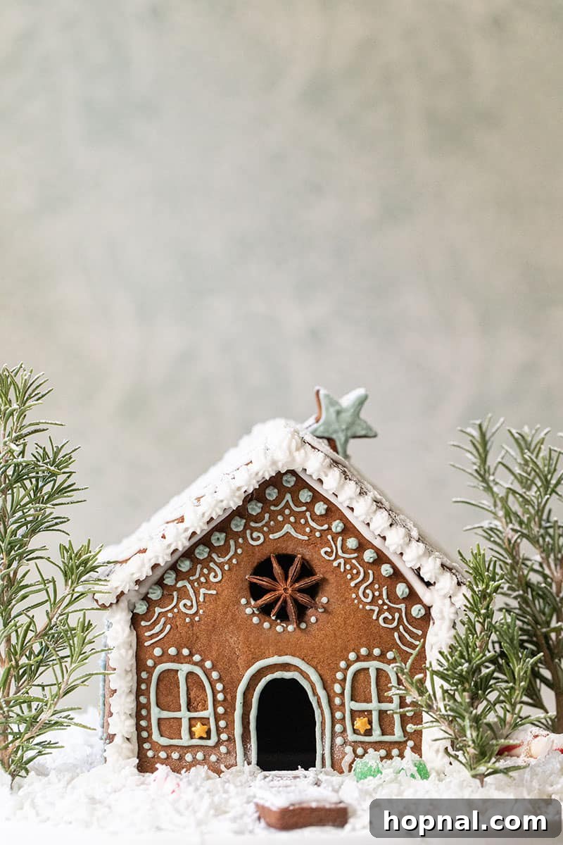 An adorable and charming gingerbread house, lovingly decorated with fluffy coconut snow on the roof and miniature rosemary trees surrounding it, creating a winter wonderland scene.