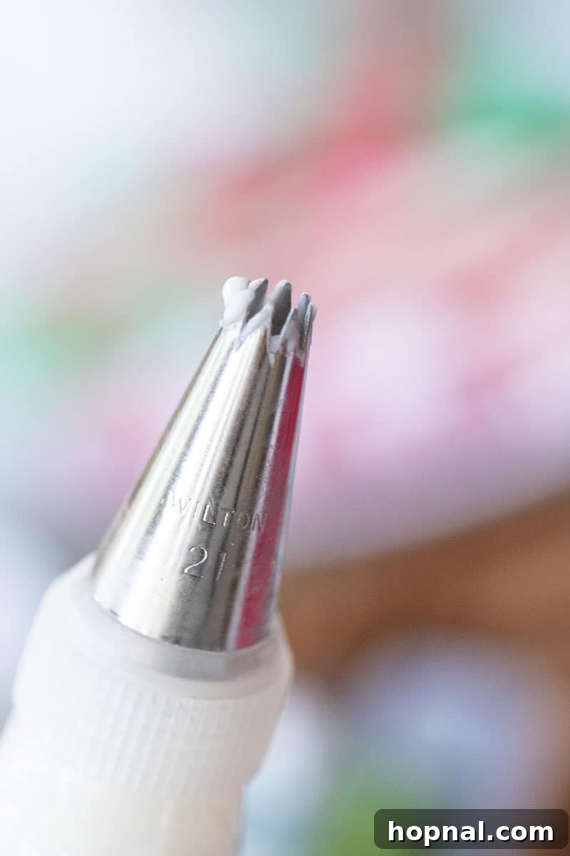 Close-up of a Wilton 10 piping tip applying a thick line of royal icing to a gingerbread house, showcasing the precise application needed for decoration.