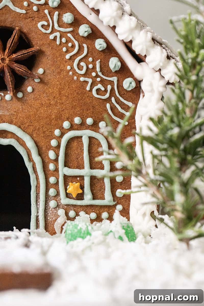 Close-up of intricate frosting details on a decorated gingerbread house, showing delicate piping work and candy adornments.