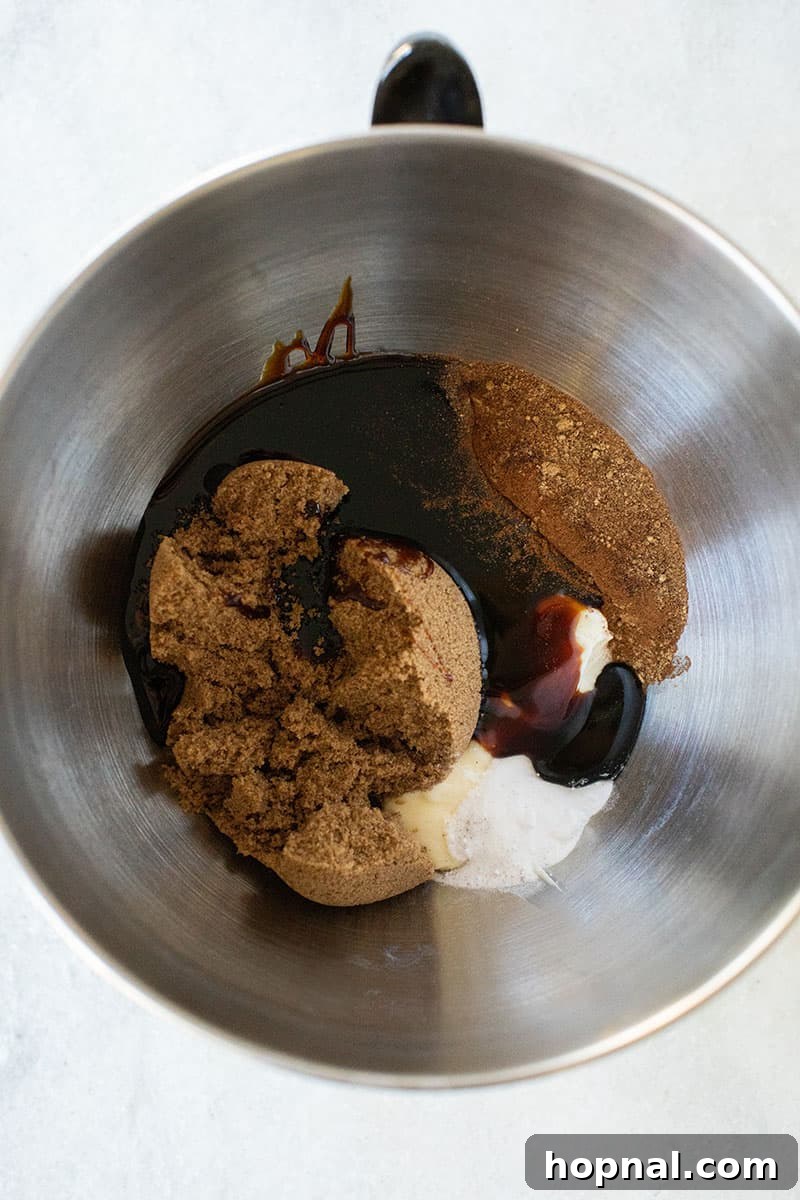Ingredients for gingerbread dough being mixed in a large bowl with an electric mixer, showing the creamy texture.