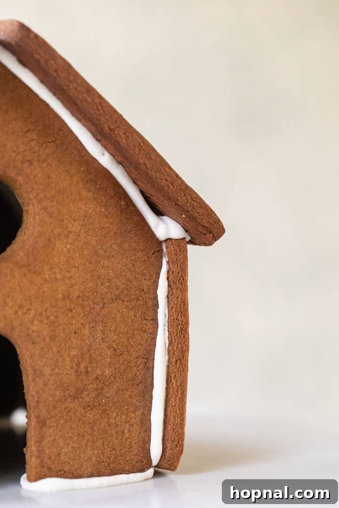 The delicate process of sticking gingerbread house walls together with royal icing, ensuring a stable structure.