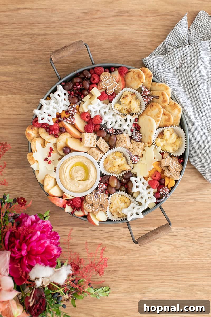 Santa's Snack Tray for Kids 2 A vibrant, round tray brimming with an assortment of mini desserts, fresh fruit, creamy hummus, and other delightful treats, artfully arranged as a festive Christmas appetizer platter for kids, perfect for holiday gatherings.