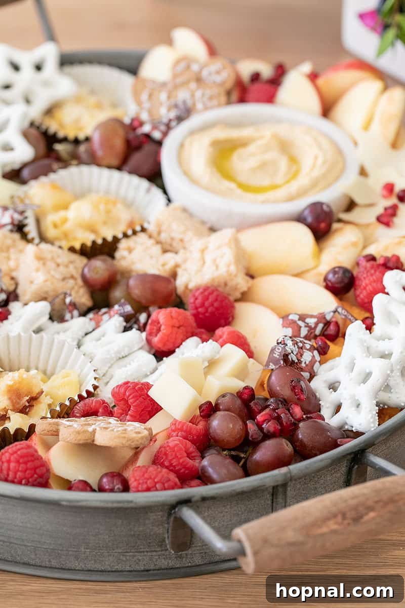 Santa's Snack Tray for Kids 4 A charming round galvanized tray elegantly filled with an array of kid-friendly Christmas appetizers, prominently featuring fresh grapes, juicy berries, and various cheeses, perfect for a festive holiday snack spread.