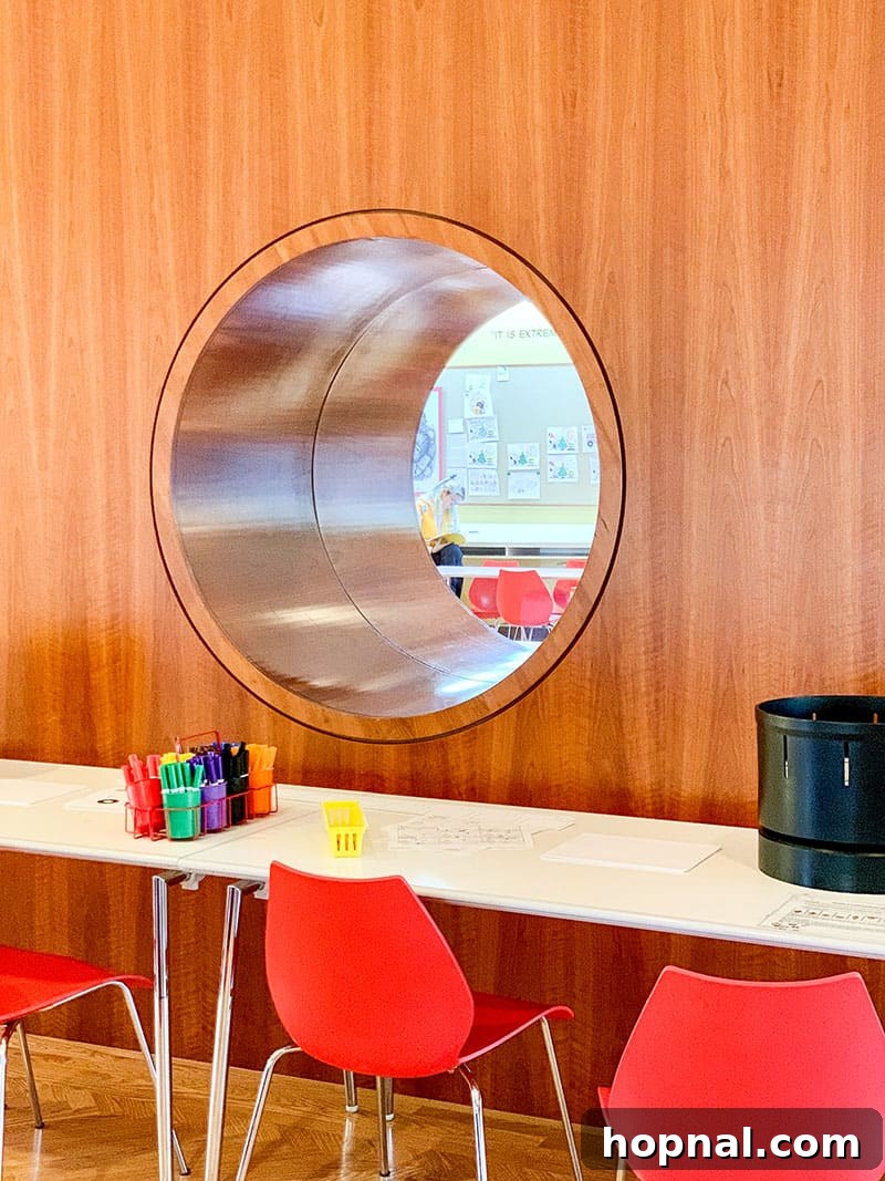 A unique wall with a round window looking into the kid's education center at the Schulz Museum