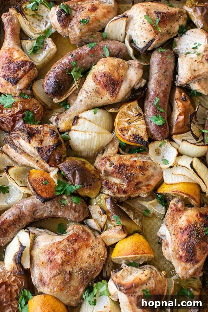 Perfectly golden brown sheet pan dinner with chicken, sausage, lemons, apples, onions, parsley and garlic.