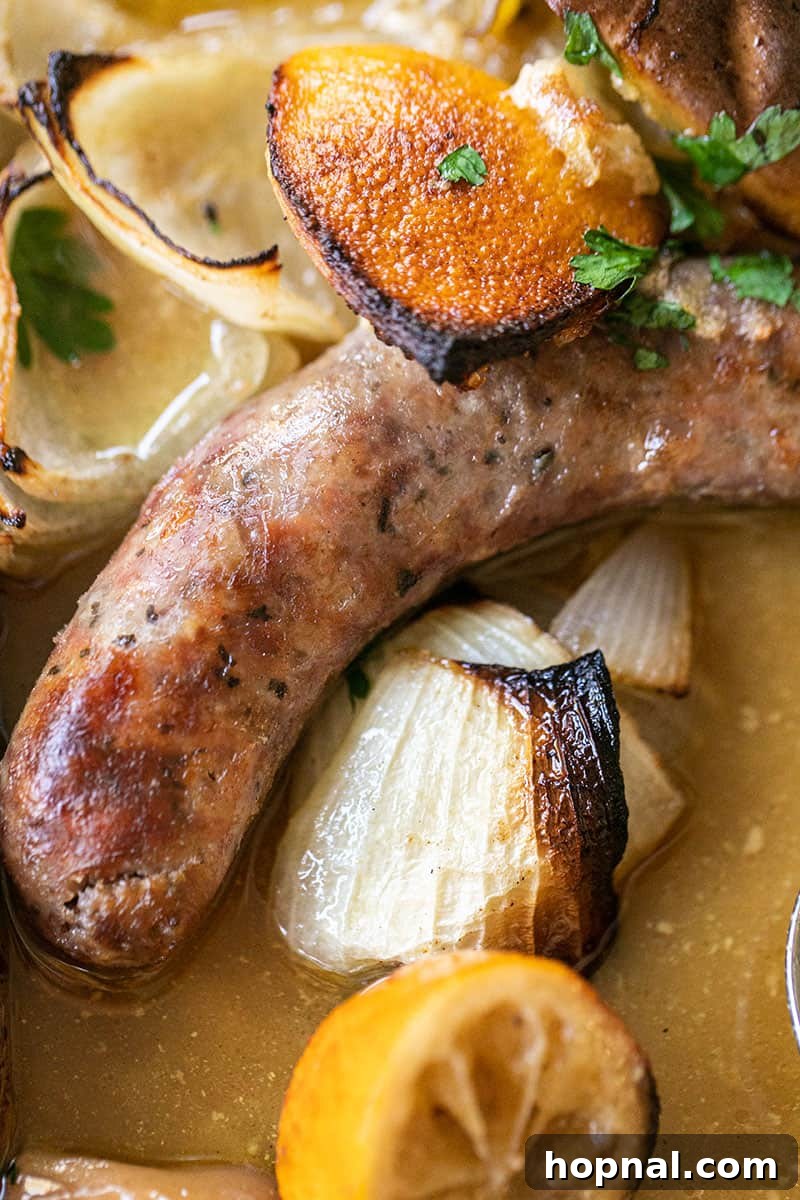 Perfectly browned Italian sausage and chicken baking with onions and lemon slices, creating rich juices.