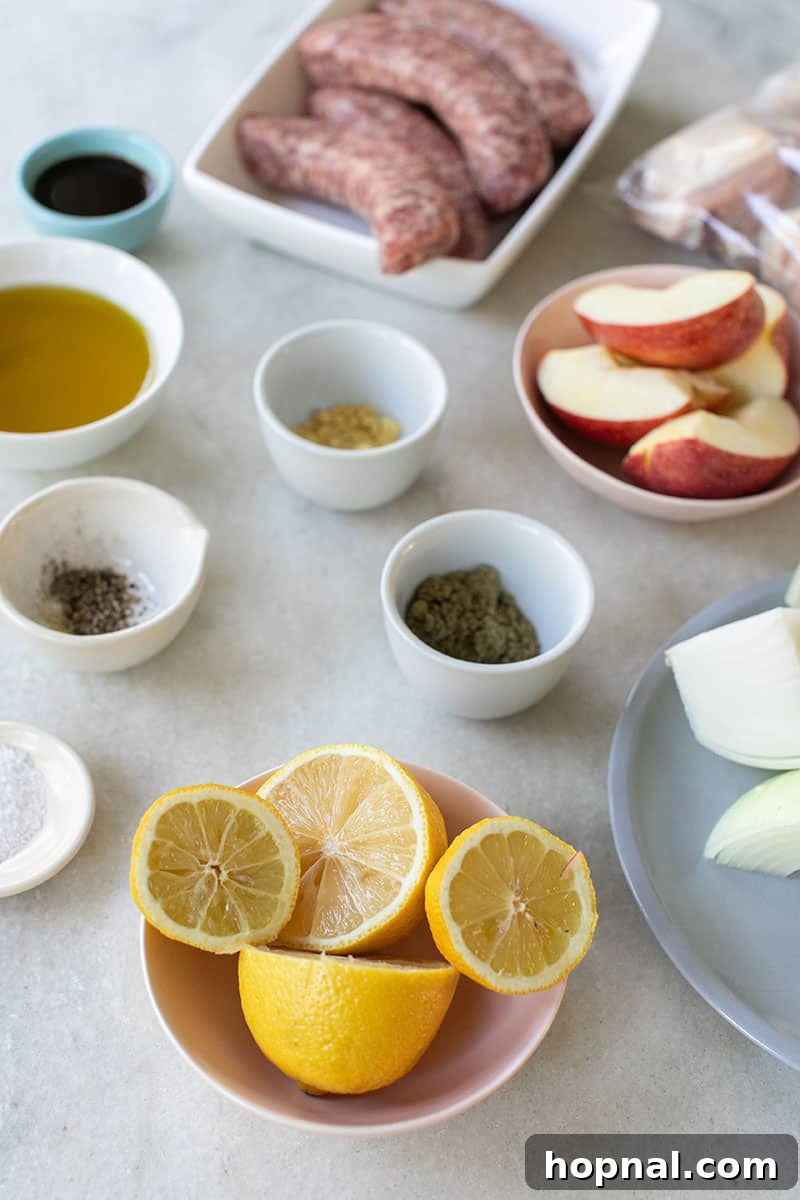 A vibrant array of spices, lemons, apples, onions, sausage, chicken, and olive oil on a marble surface, ready for the one-pan chicken and sausage bake.